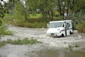 A van caught in floodwaters with trees and grass around.