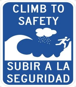 A bilingual sign saying "Climb to Safety" with a pictogram of a person ascending and symbols representing water below.