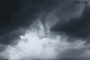 A dark stormy sky with a visible tornado funnel cloud forming.
