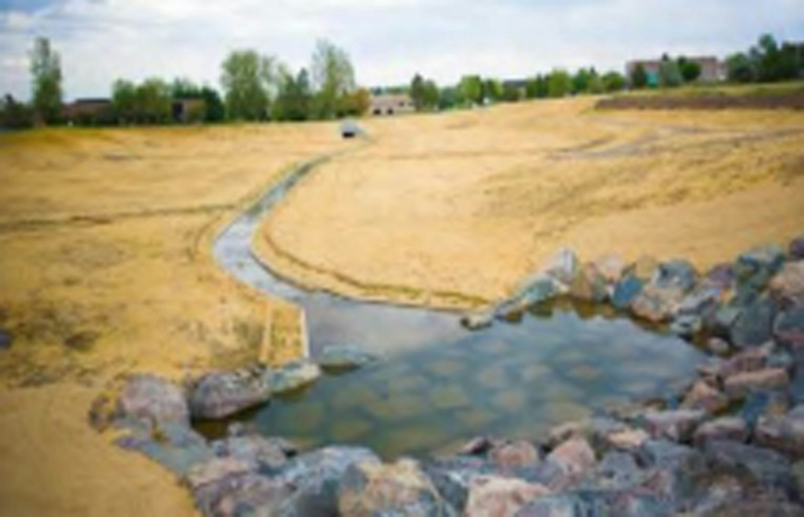A man-made water feature with rocks surrounded by a parched landscape.