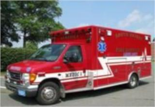 A red ambulance parked on the street with trees in the background.