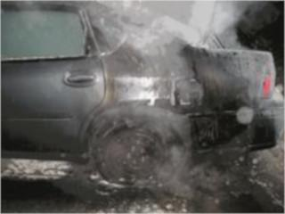 A car with smoke and signs of damage around the rear wheel area.