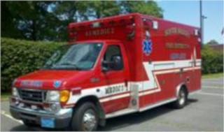 A red ambulance with emergency markings parked on a road.
