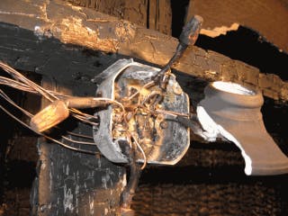 A charred electrical junction box with burned wires and damage, likely from a fire.