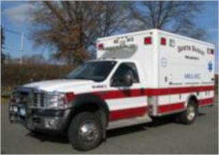 An ambulance parked on a street with trees in the background.