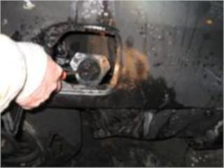 A hand opening a car’s fuel cap on a dirty vehicle.