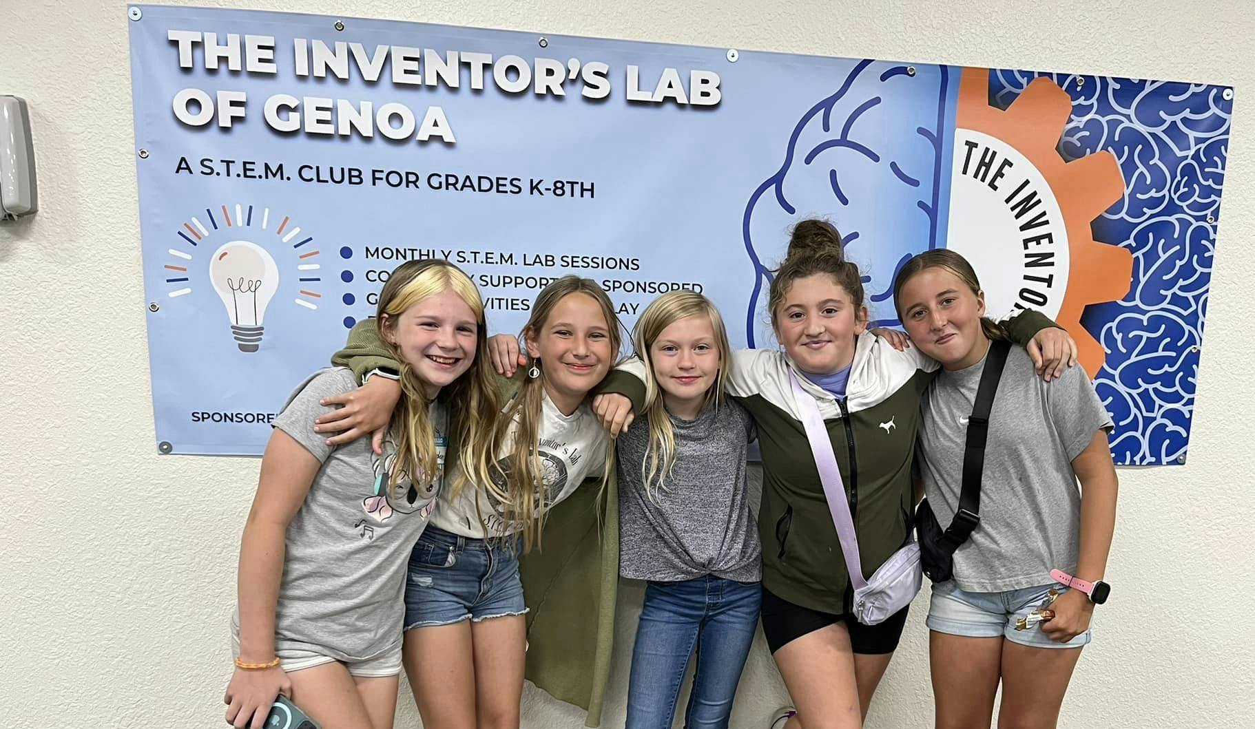 Five kids posing in front of a STEM club banner.