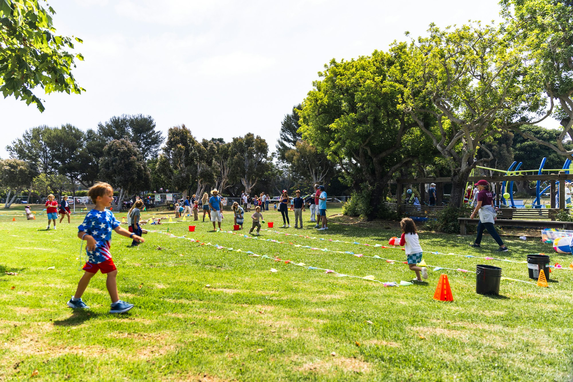 People playing and having fun in a park with cones and ropes set up for activities.