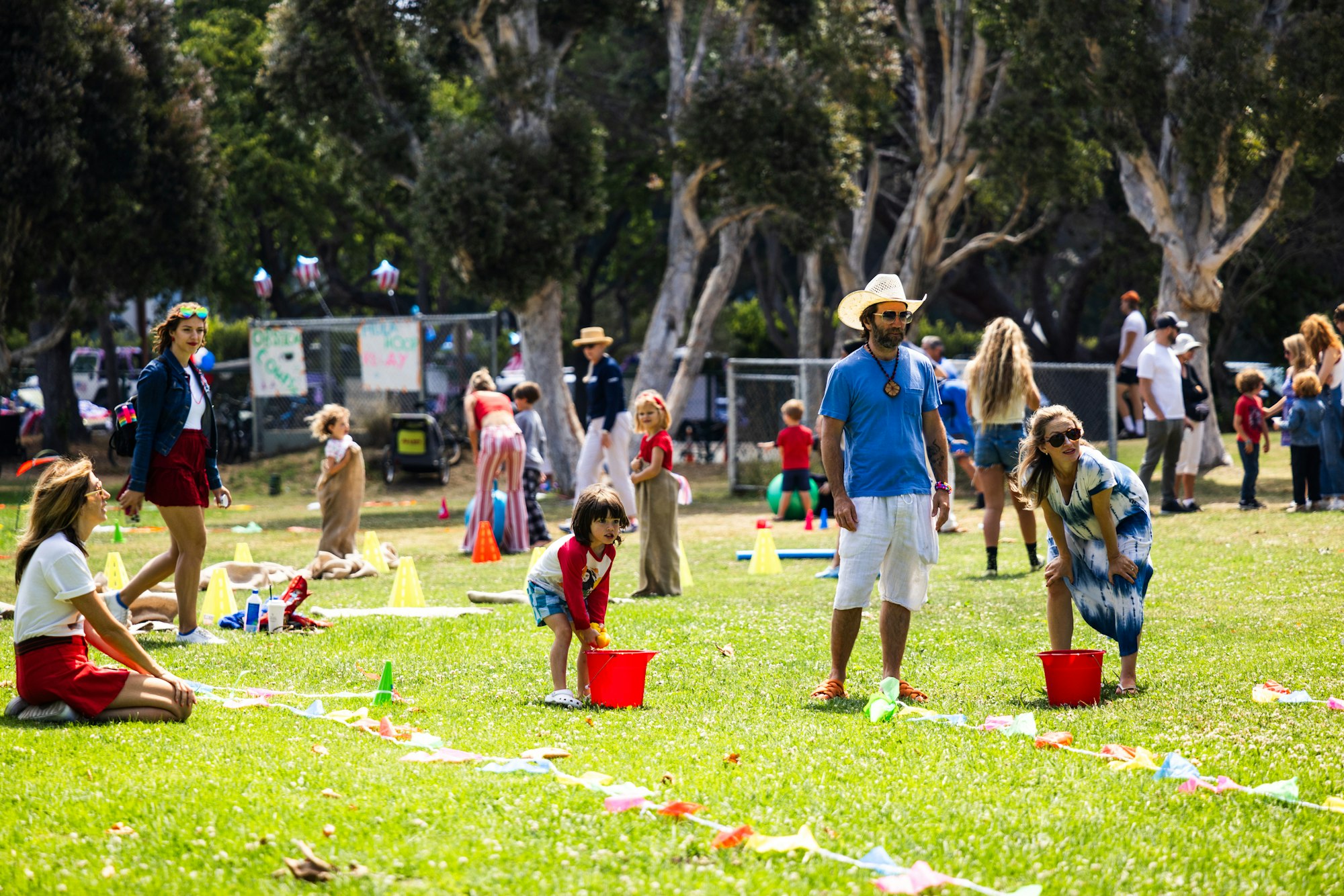 People enjoying a lively outdoor event, with games and activities for children and adults in a park setting.