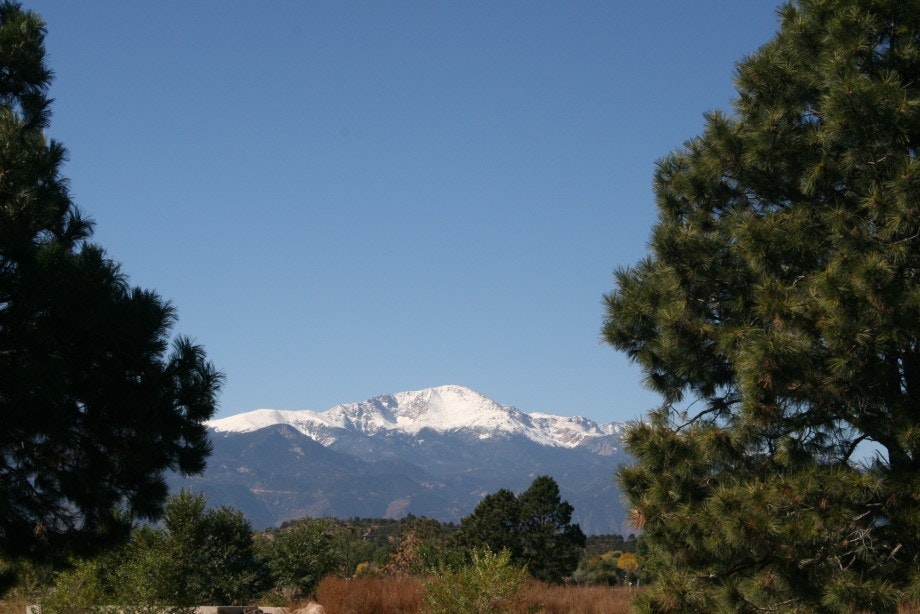Snow-capped mountain backdrop, clear sky, pine trees in the foreground.