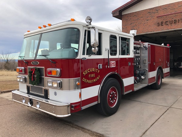 A red fire truck from the Security Fire Department parked outside a fire station.