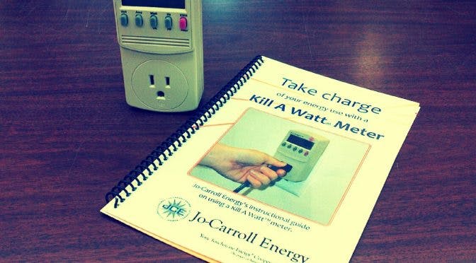 An outlet power meter and an instructional guide booklet on a table.