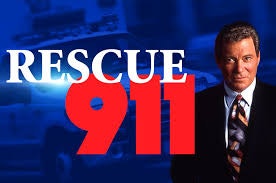 A person in a suit stands beside bright text "Rescue 911" with an emergency vehicle in the background.