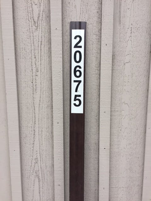 The image shows a vertical post with the number "20675" prominently displayed on it, against a textured wall.