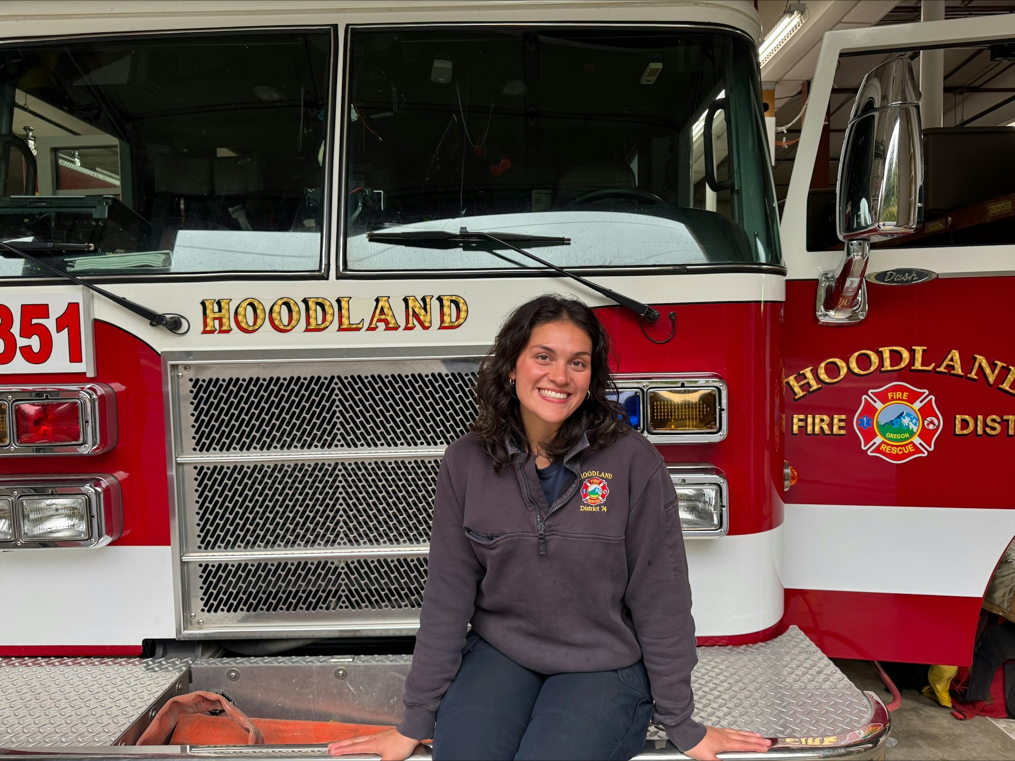A person sitting in front of a red fire truck labeled "HOODLAND".