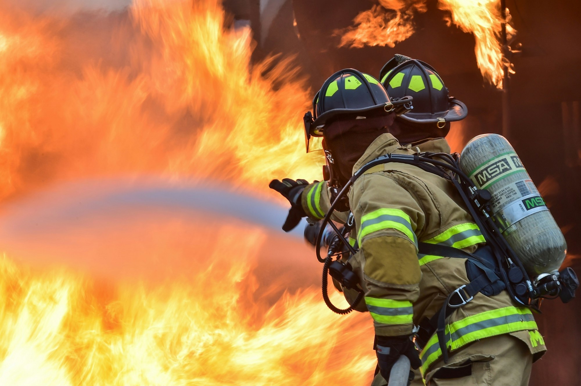 Firefighters with a hose battling a fierce blaze.