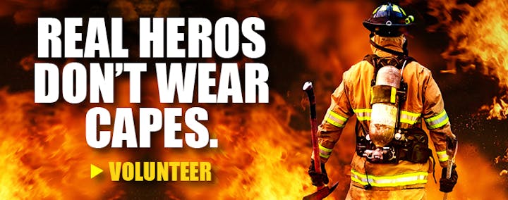 A firefighter among flames with text: "Real heroes don't wear capes. Volunteer."