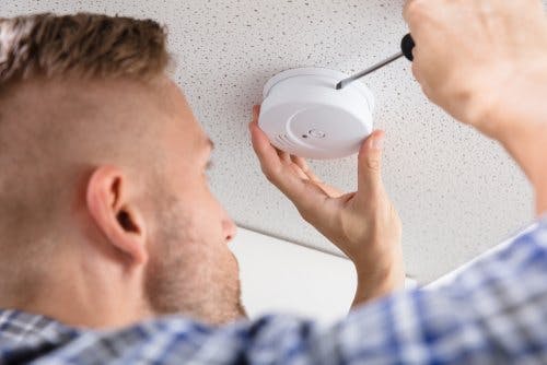 Person installing or fixing a smoke detector on the ceiling.