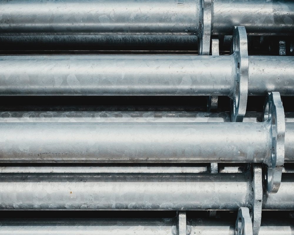 Stacked metal pipes with flanges, arranged horizontally.