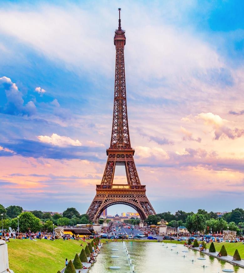 The image features the Eiffel Tower in Paris, surrounded by green gardens and people, under a colorful sky at sunset.