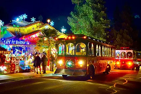 A festive scene featuring a decorated house with colorful lights and a vintage trolley bus during a nighttime holiday celebration.