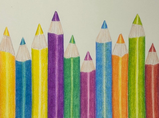Colored pencils in various vibrant shades are arranged upright on a light background.