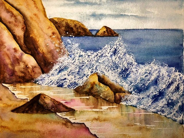 Rocky coastline with waves crashing, featuring sandy beach and blue water.