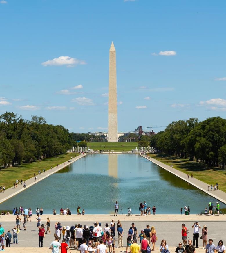 A bright day at the National Mall featuring the Washington Monument, reflecting pool, and lots of visitors enjoying the scenery.