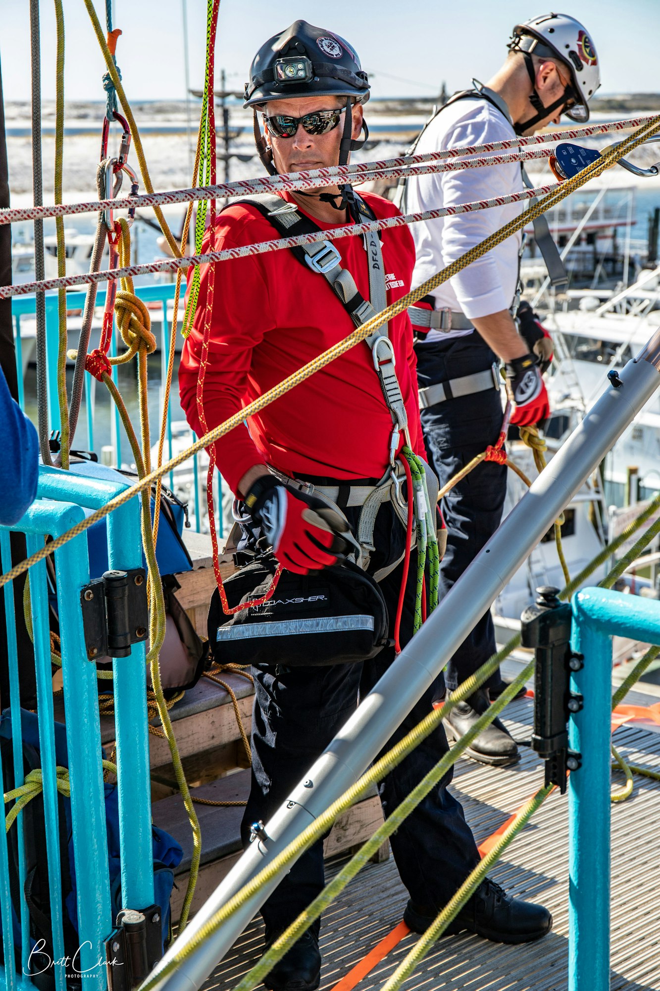 Two people in safety gear, helmets, and harnesses amidst colorful ropes on a structure.