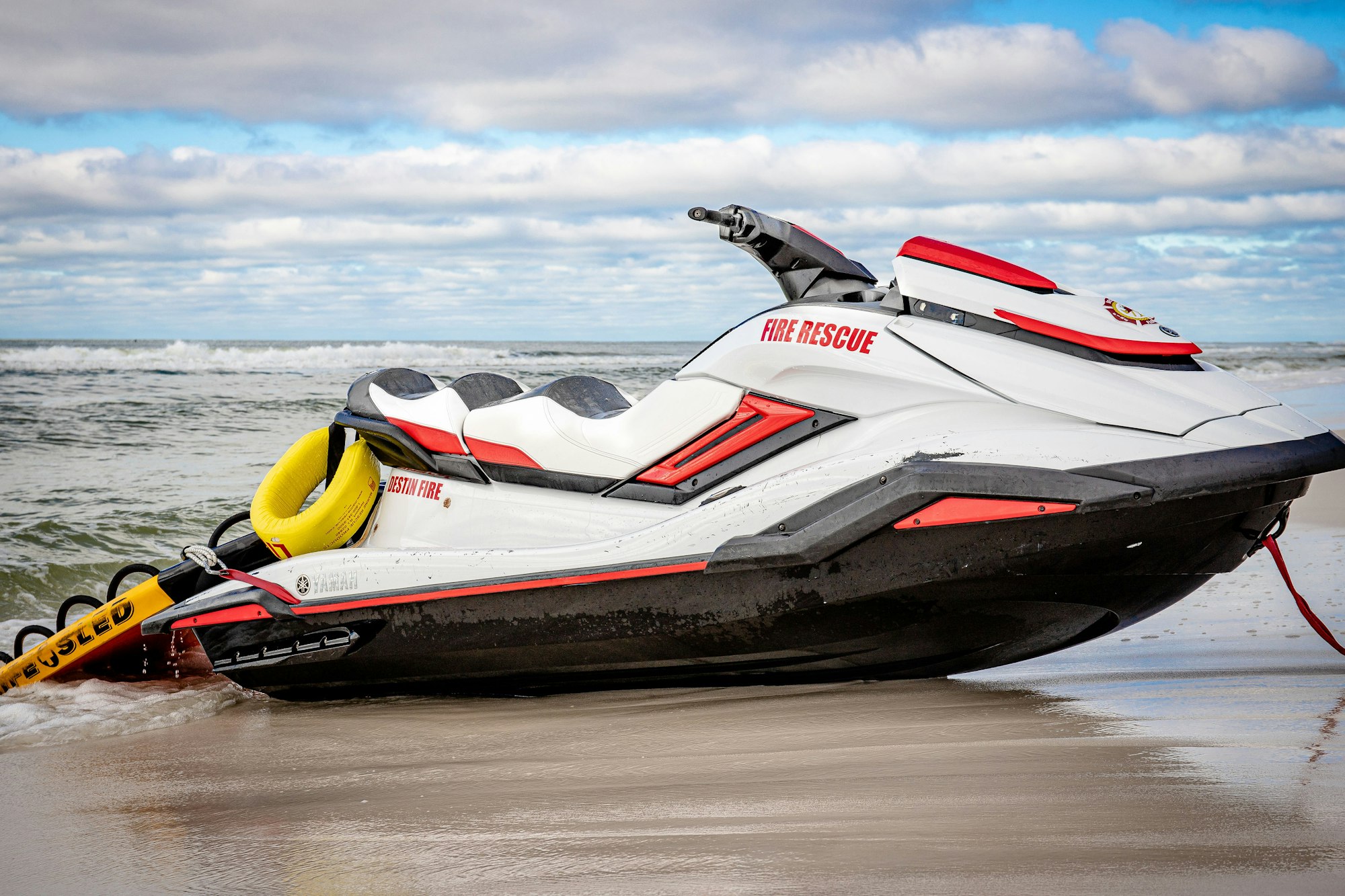 A fire rescue jet ski on a beach with waves in the background.