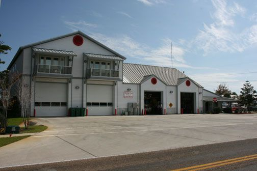 A modern fire station with multiple garage bays and a road in the foreground.