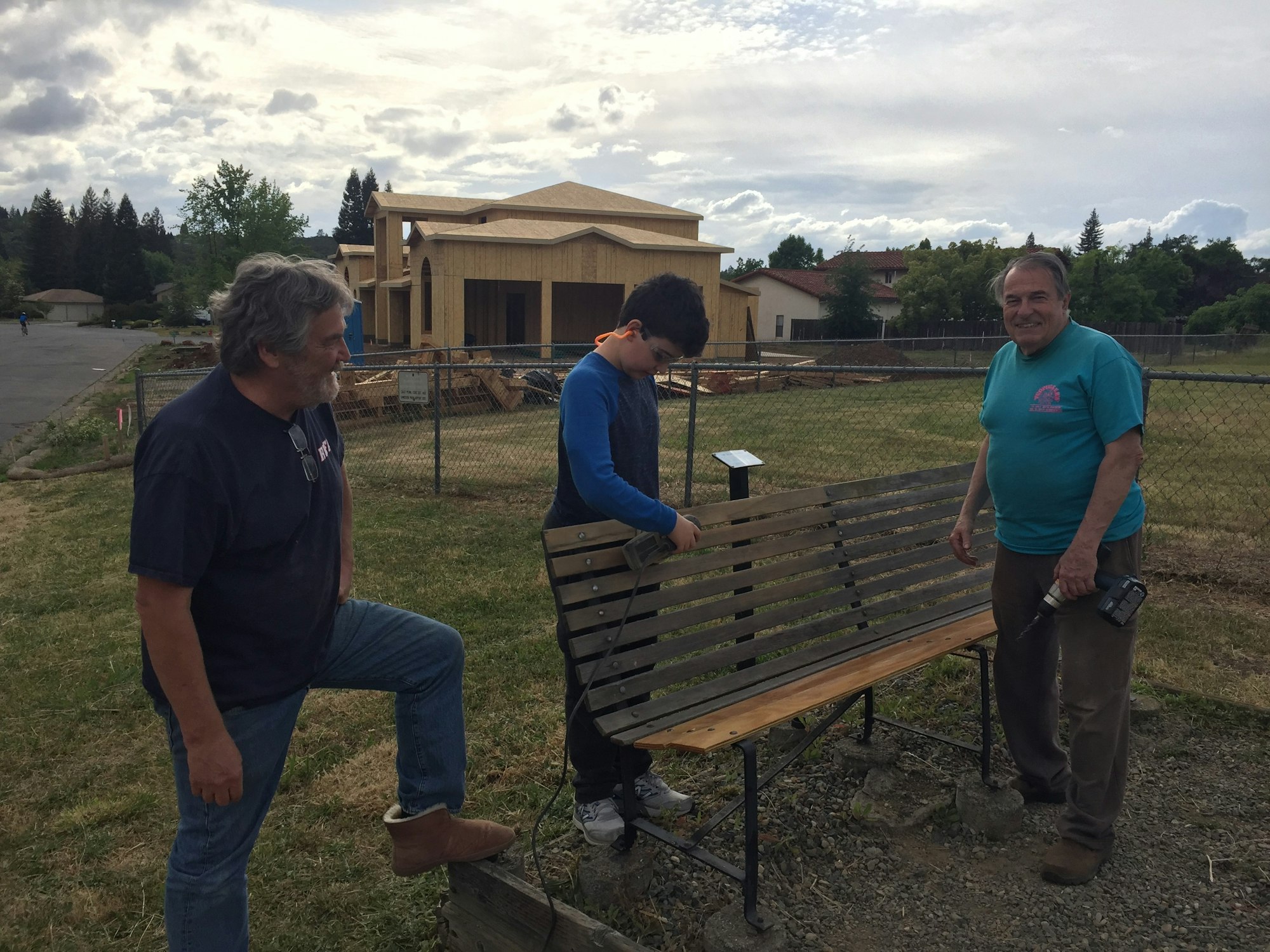 Three men next to a park bench they are repairing