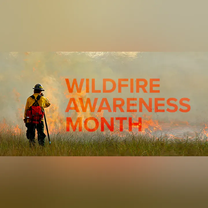 The image promotes "Wildfire Awareness Month," featuring a person in a yellow outfit near flames.