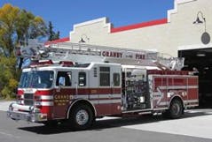 A red and white fire truck parked outside a fire station.