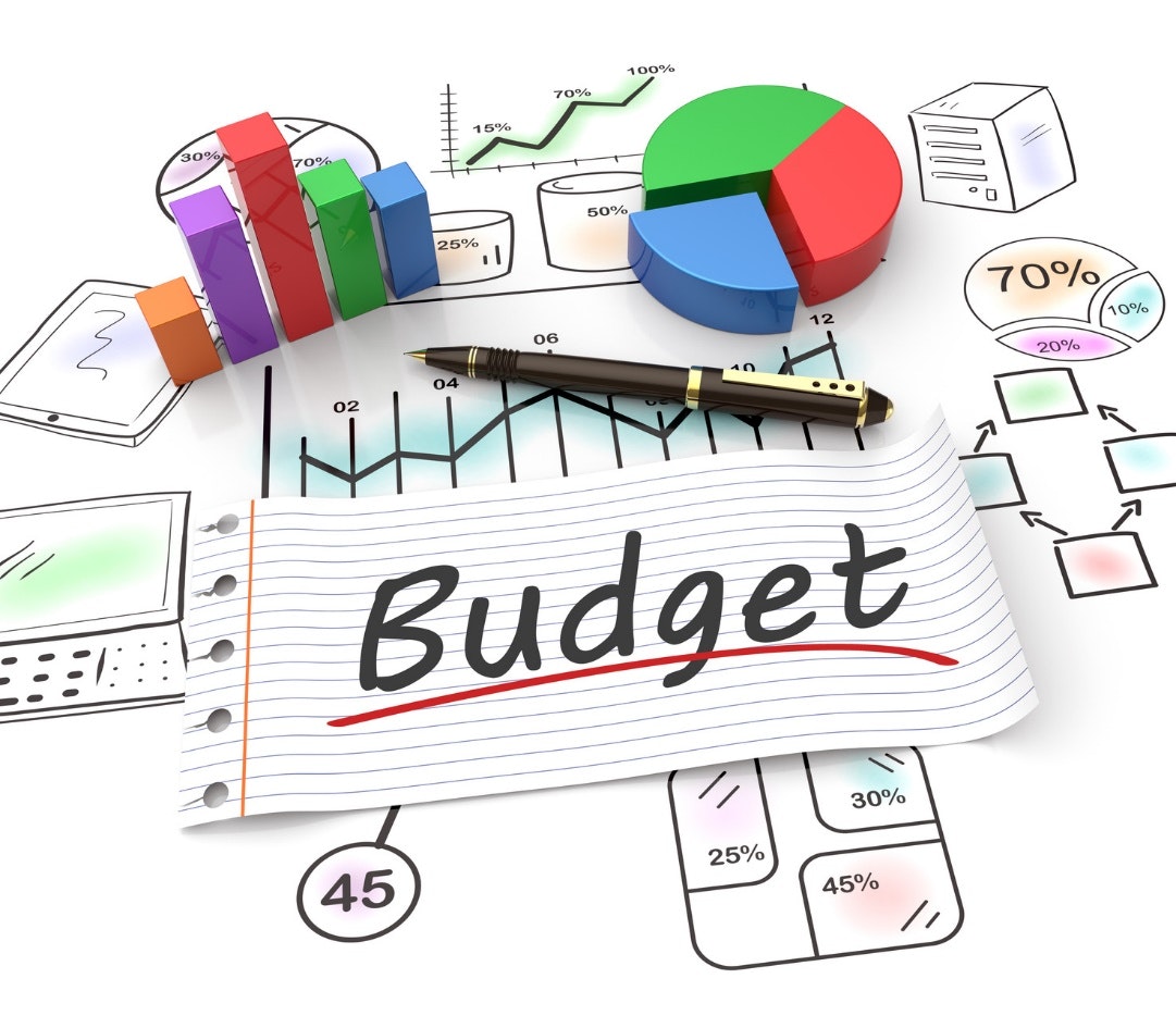 Charts and graphs with a notebook paper labeled "Budget" and a pen.