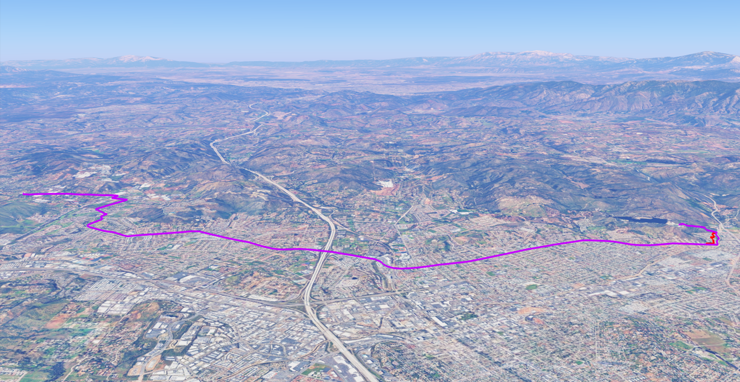 An aerial view showcasing a winding route in a mountainous landscape with a purple line marking the path through urban and rural areas.
