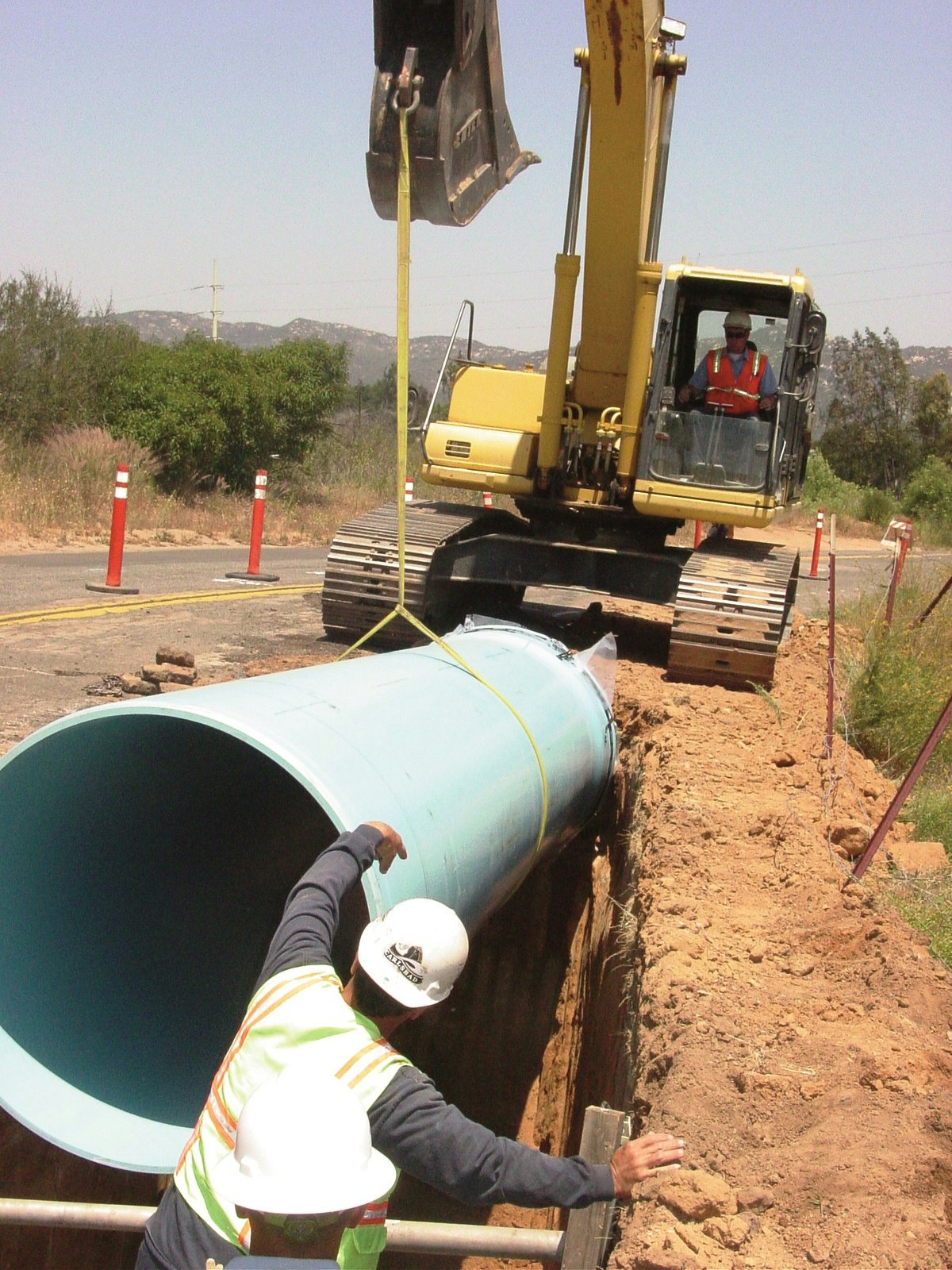 May contain: VID staff placing new pipeline into trench with crane