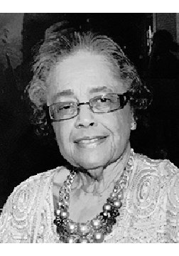 Elderly person wearing glasses and a beaded necklace, smiling. Black and white photo.