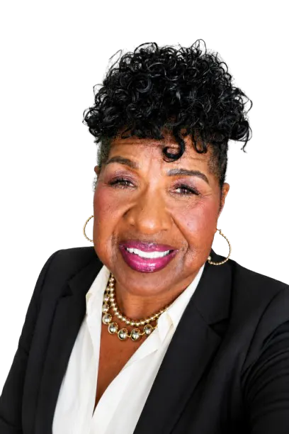 The image features a smiling person with curly hair, wearing a black blazer and a statement necklace, against a plain background.