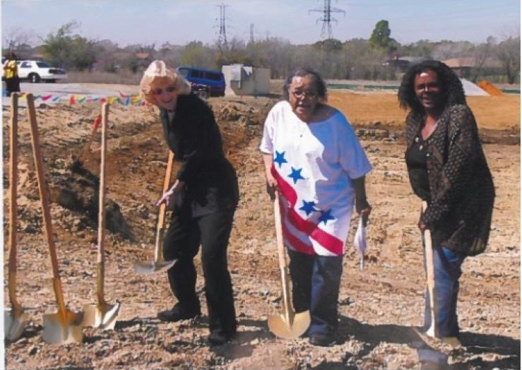 Three people at a groundbreaking ceremony with shovels.