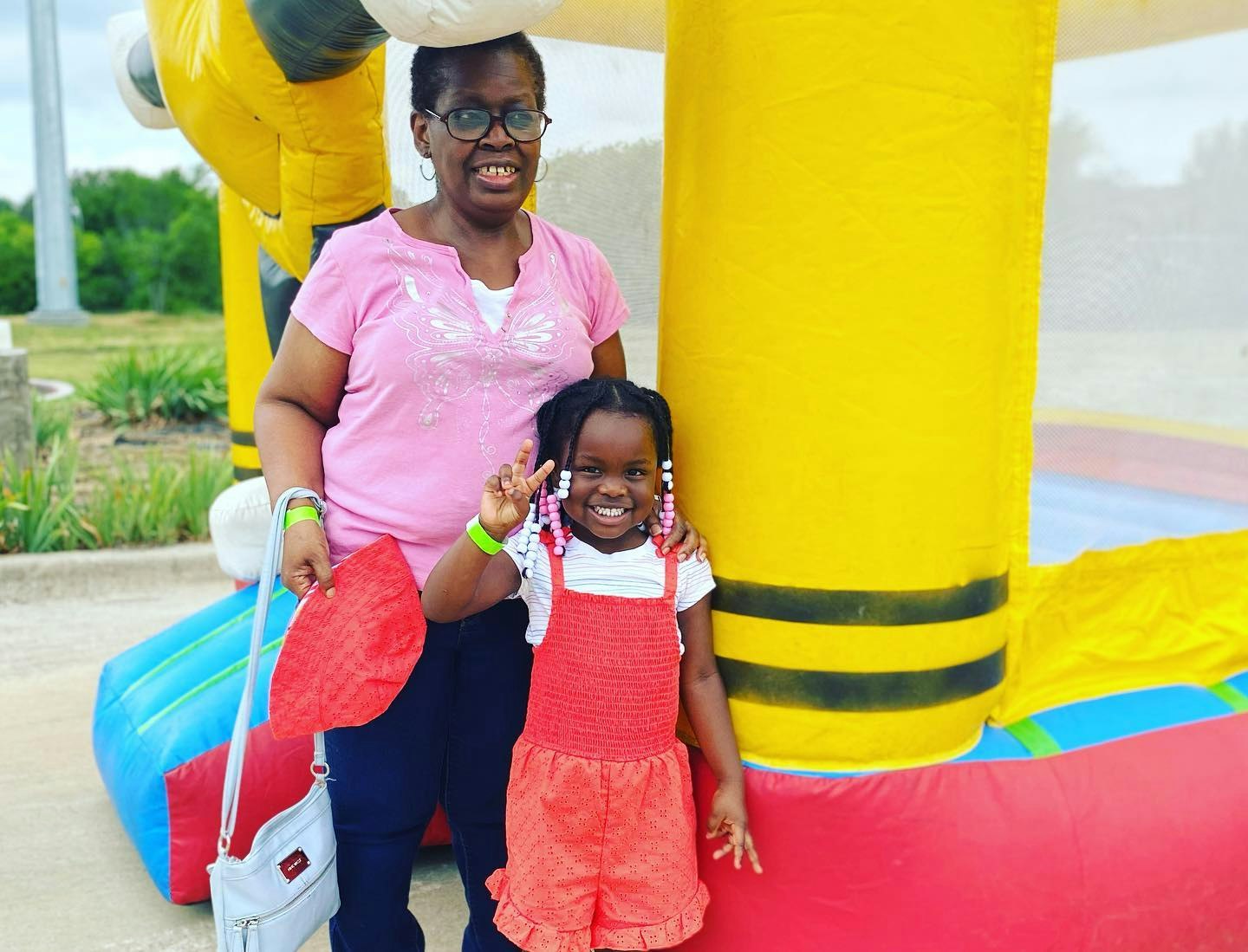 A woman and a child posing in front of a yellow inflatable bounce house.
