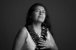 A person in a confident pose wearing a bandolier, captured in black and white.