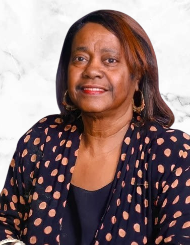 A woman wearing a polka dot top poses against a light background.