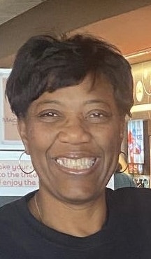 A person smiling directly at the camera in an indoor setting.