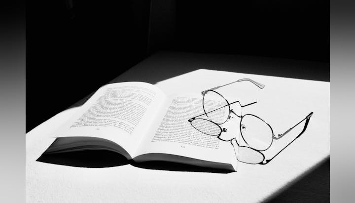 glasses laying with an open book on white tabletop