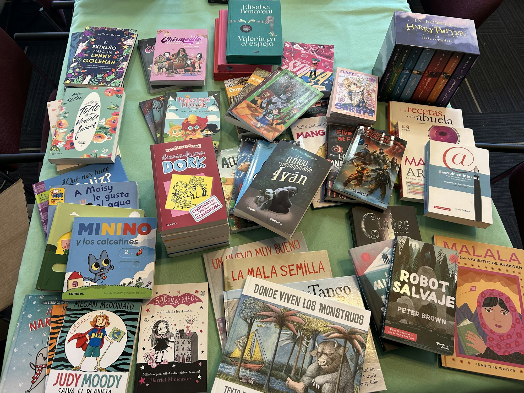 A collection of various Spanish language books, including children's, young adult, and adult titles, displayed on a table.