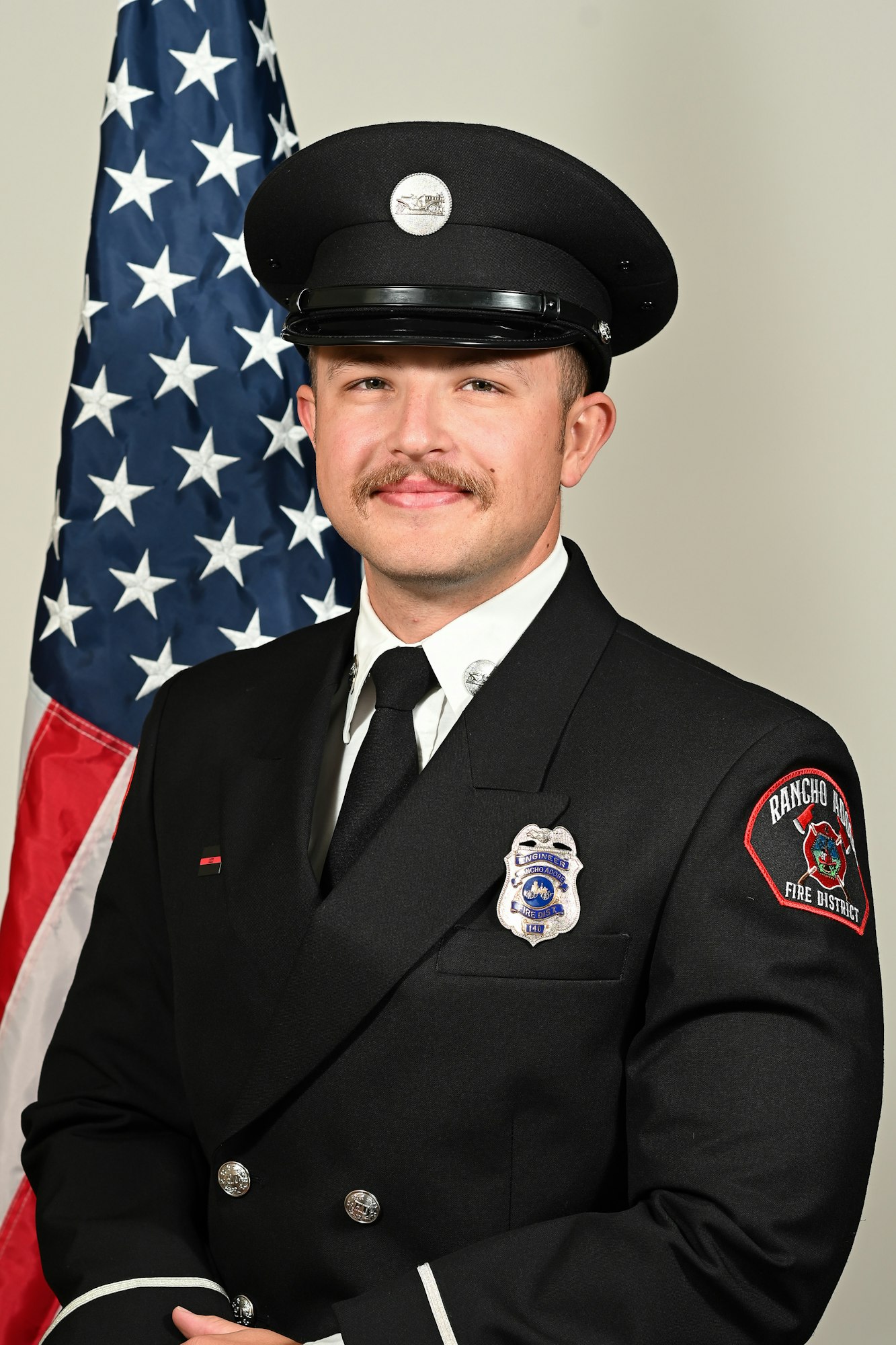 A firefighter in uniform with an American flag backdrop.