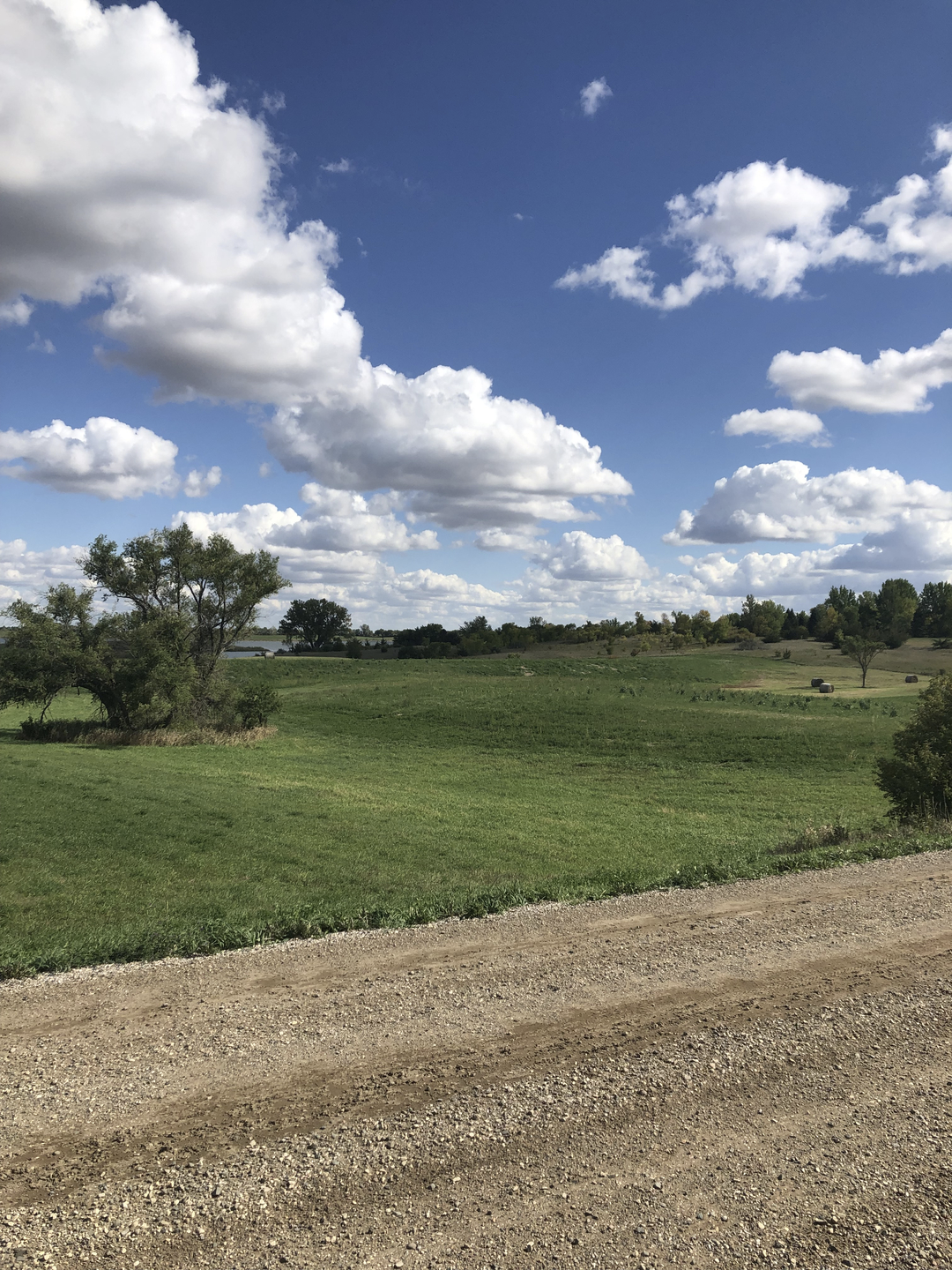 May contain: nature, outdoors, sky, gravel, road, cloud, cumulus, weather, field, grassland, ground, grass, plant, and horizon