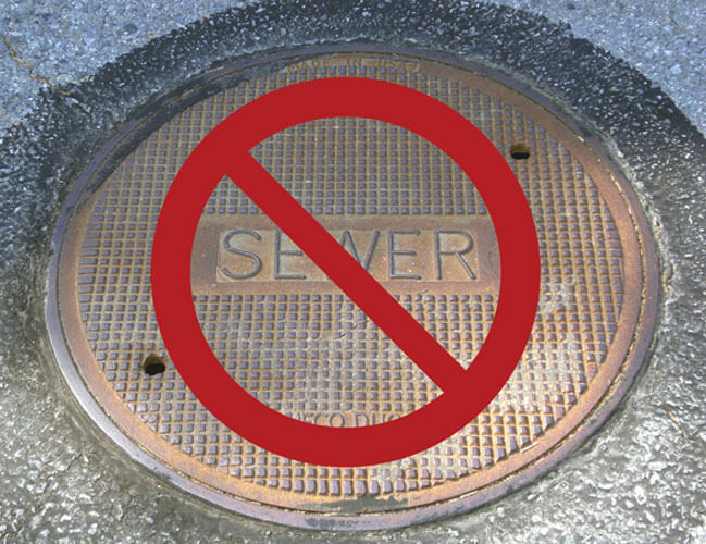 No rain water to sewer. A sewer cover with a red prohibition sign over it.