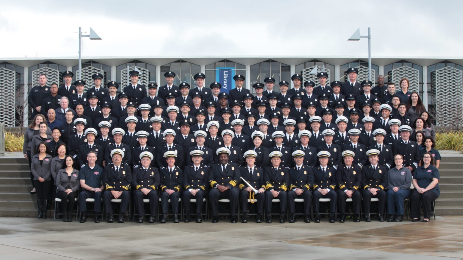 A large group of people in uniform posing for a group photo in front of a building.